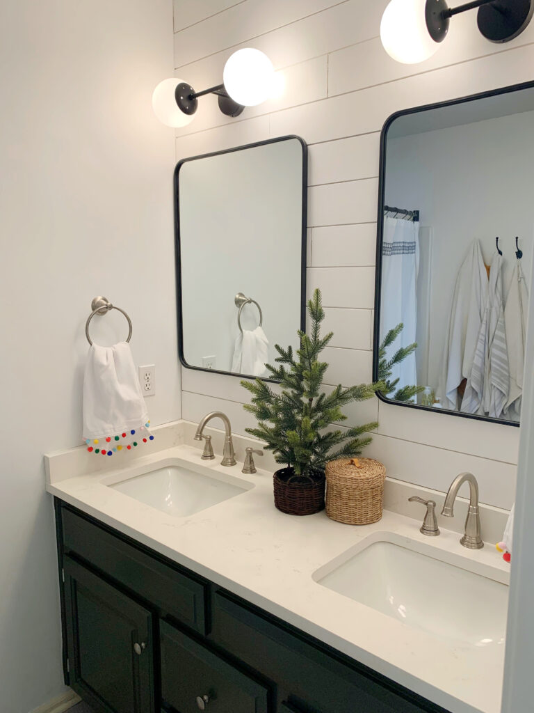 Christmas decorated guest bathroom with a dark green vanity.