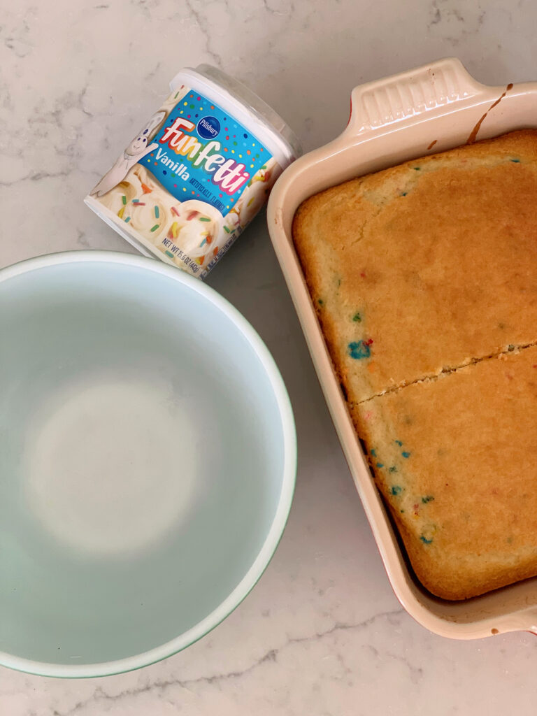 baked cake in pan, frosting and mixing bowl