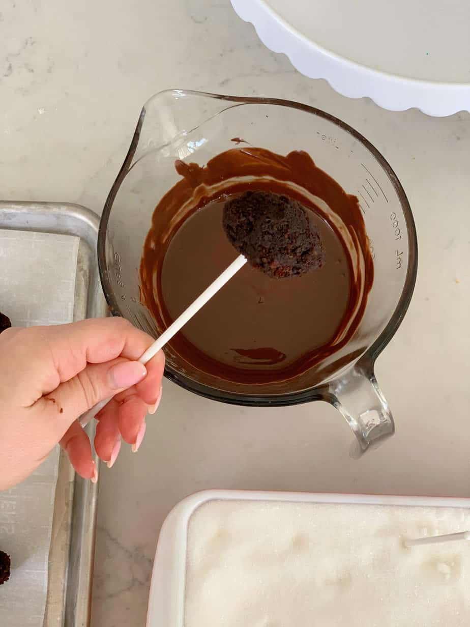 cake pop being dipped into chocolate. 