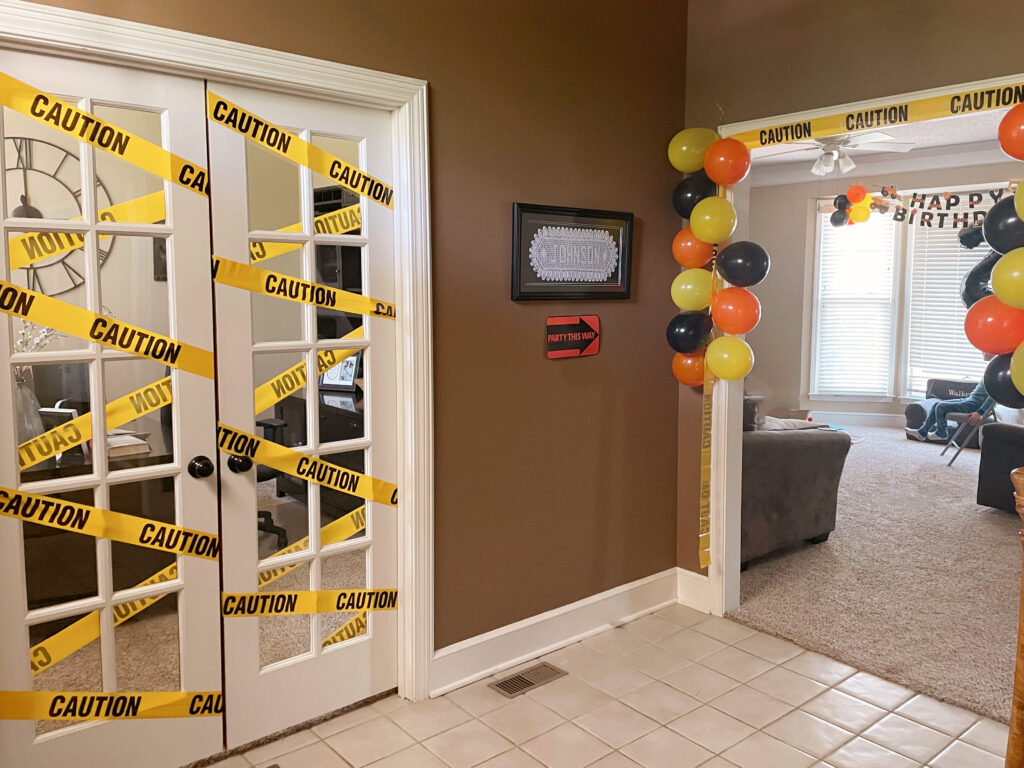 room decorated with caution tape and balloons. 