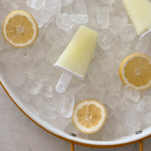 lemonade popsicles and lemon slices on ice on a serving tray.