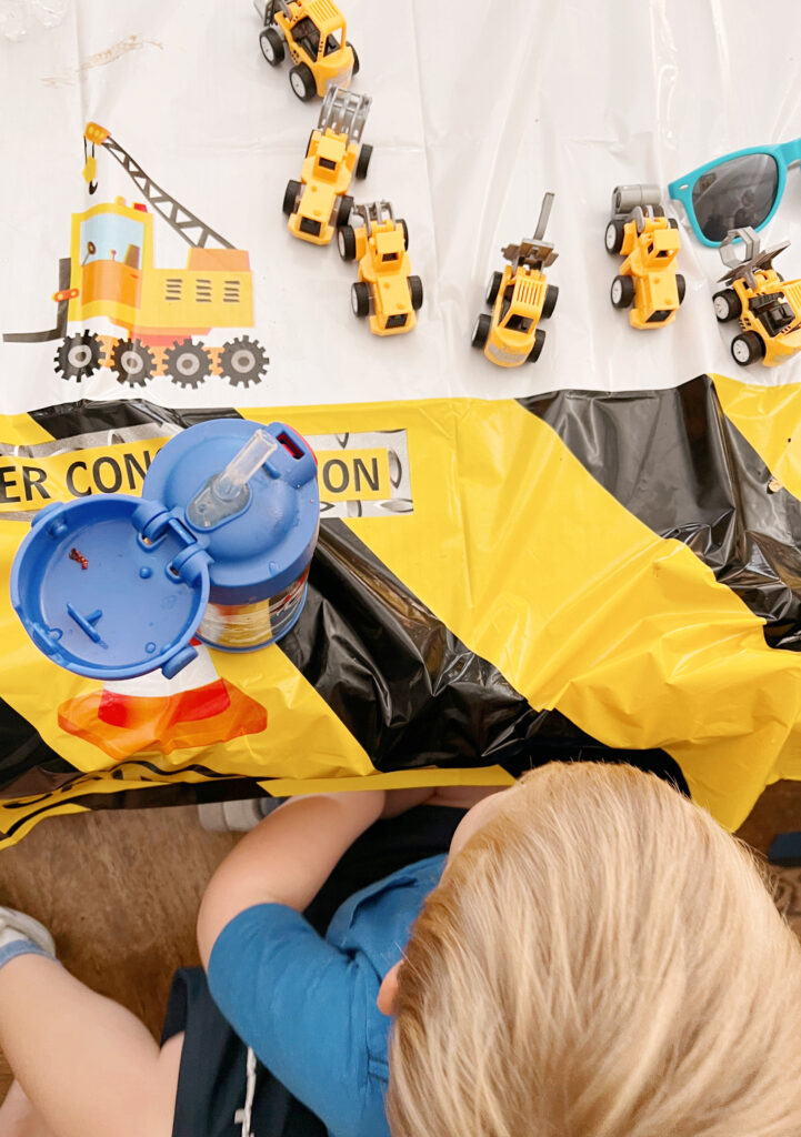 child sitting at a table with construction toys and water bottle. 