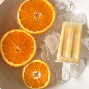 orange slices with an orange creamsicle popsicle on ice in a bowl