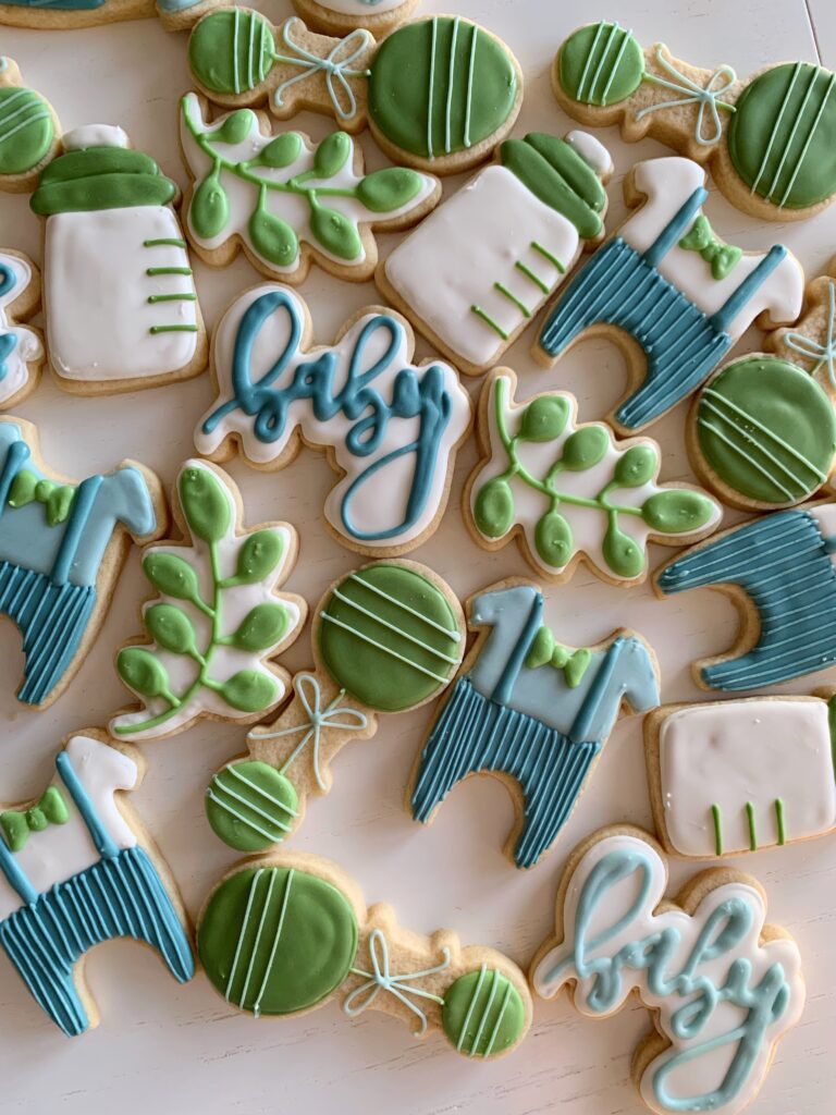 Sugar cookies shaped into suits, baby bottle, rattle and leaf. 