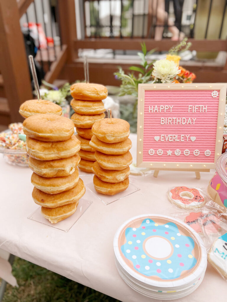 Stacked donuts on table next to pink letterboard sign. 