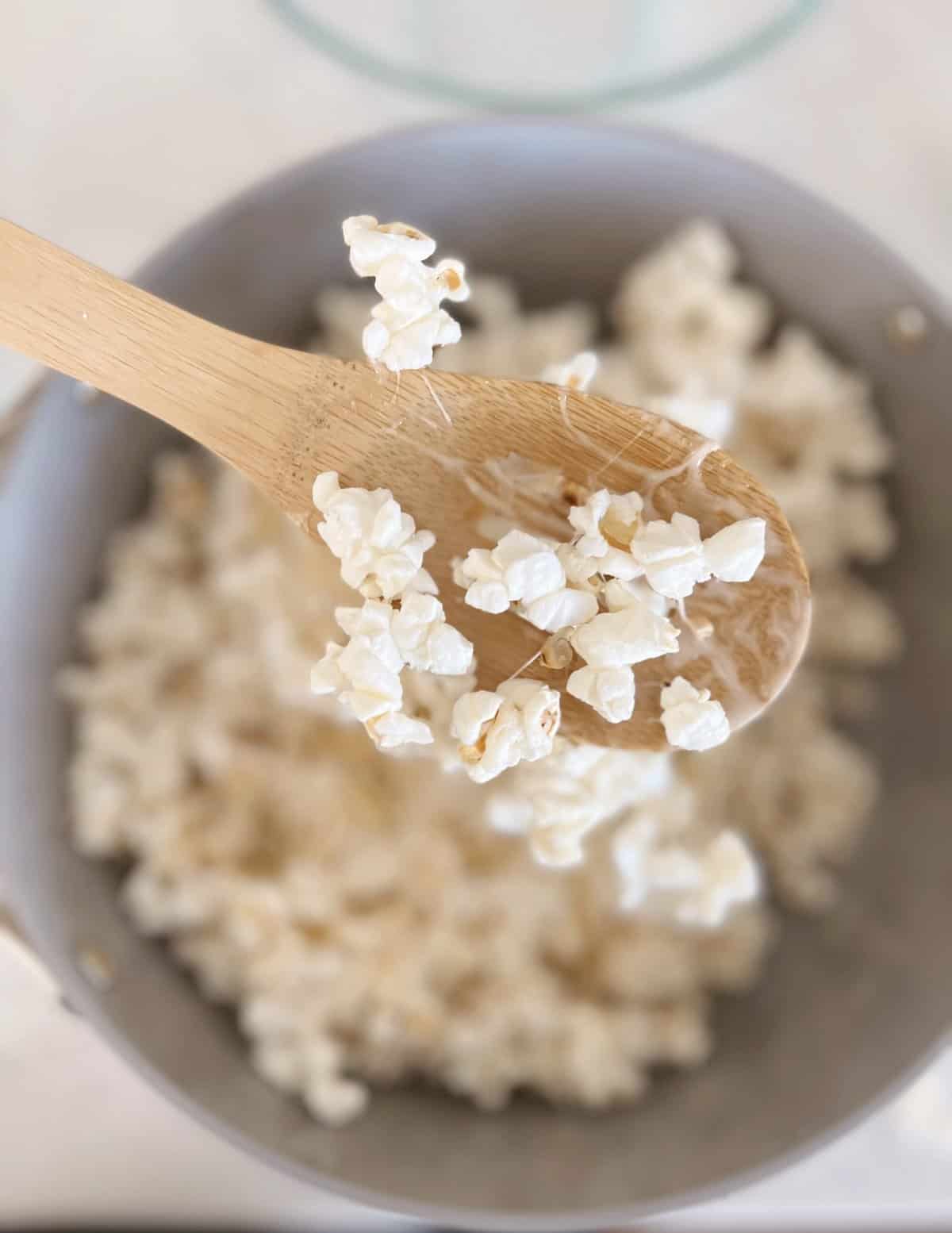 Popcorn coated in marshmallows on a wooden spoon. 
