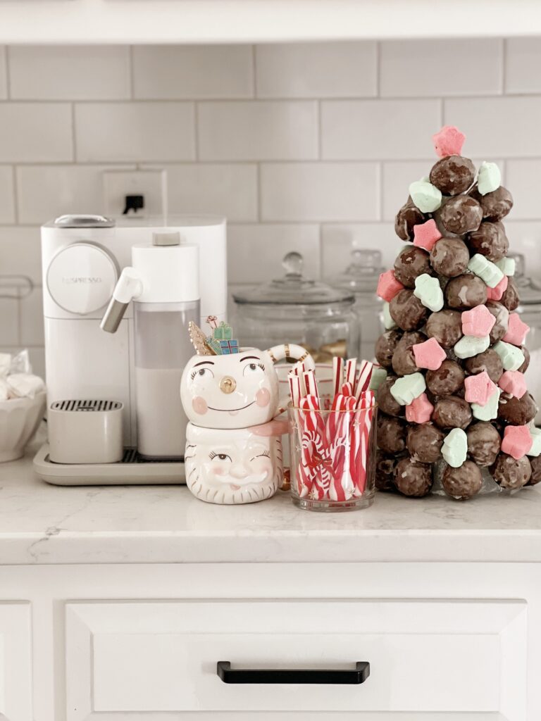 donut hole Christmas tree on counter next to epresso machine and Christmas coffee mugs. 