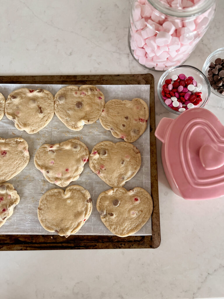 heart-shaped chocolate chip cookies on baking sheet. 