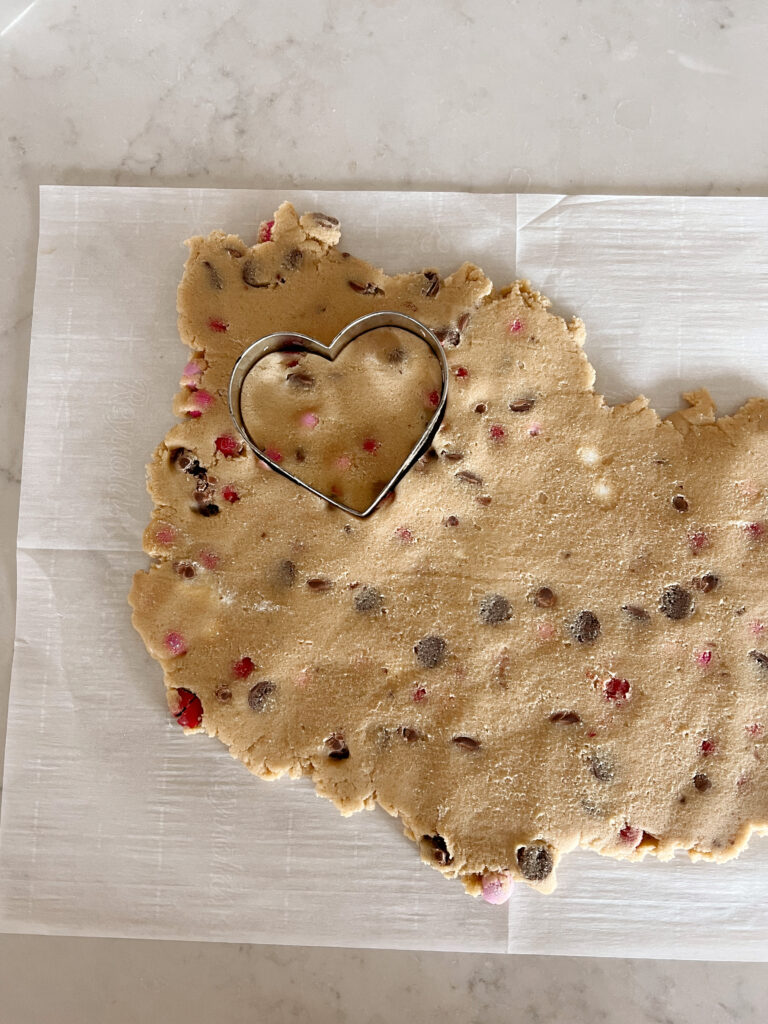 cookie dough being cut into a heart shape. 