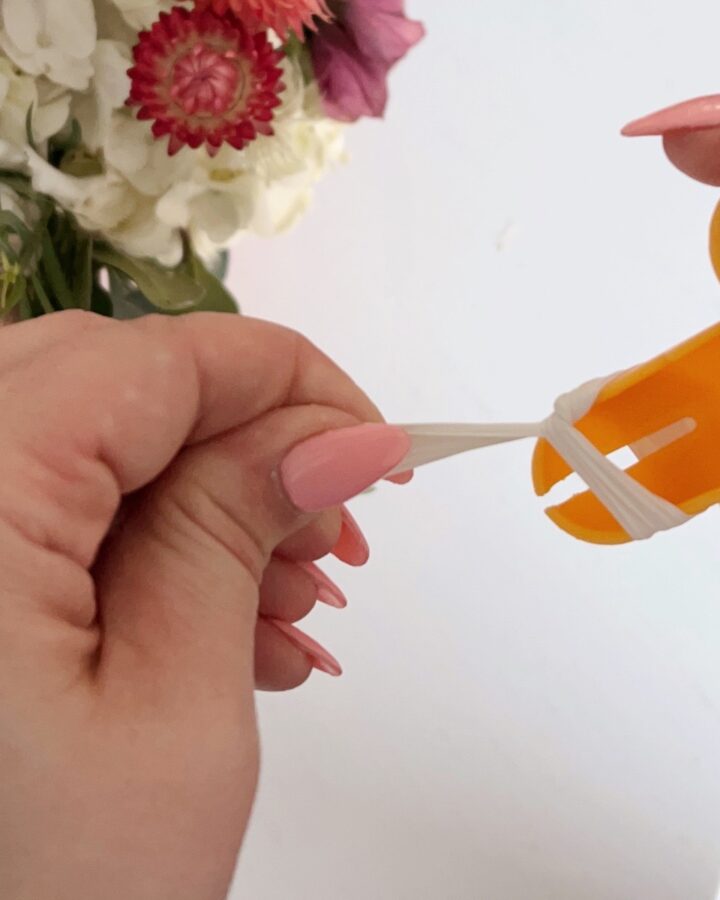 hand holding a balloon tying tool to make a knot.