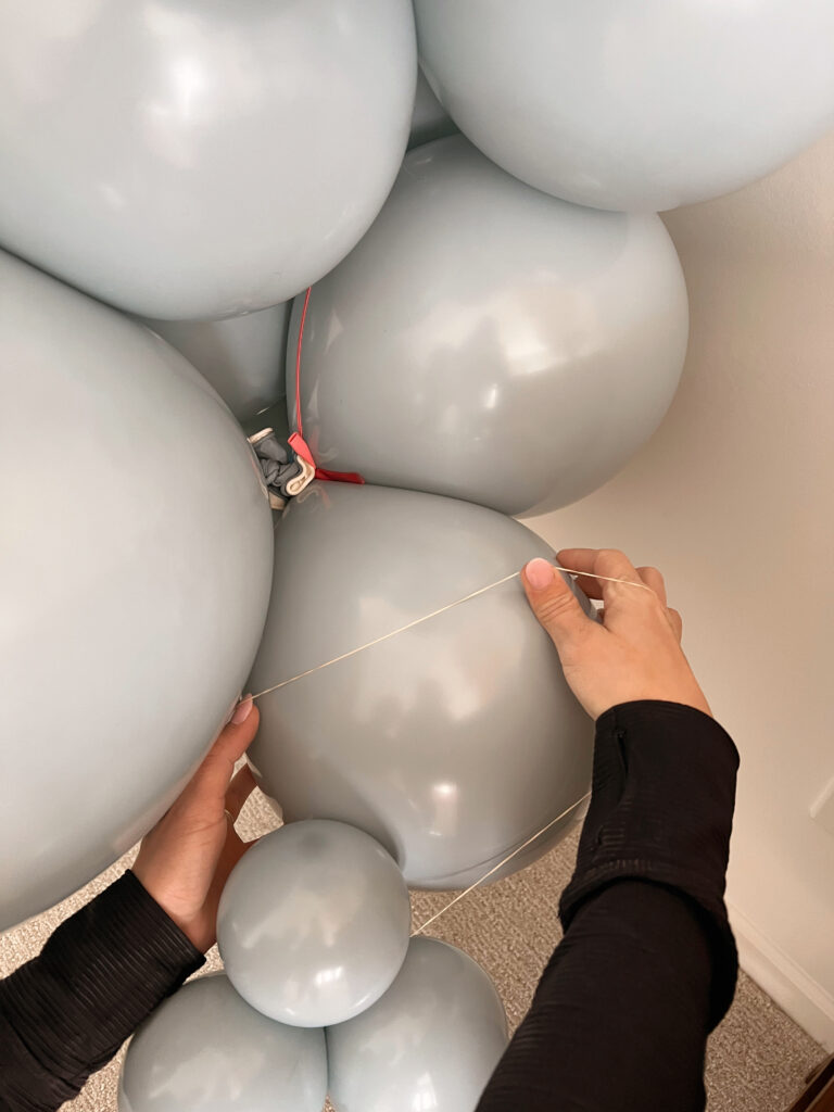 ruuberband adding small balloons to a garland. 