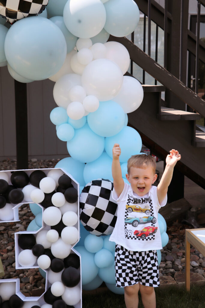 Child in front of blue balloons and number 3 balloon mosaic. 