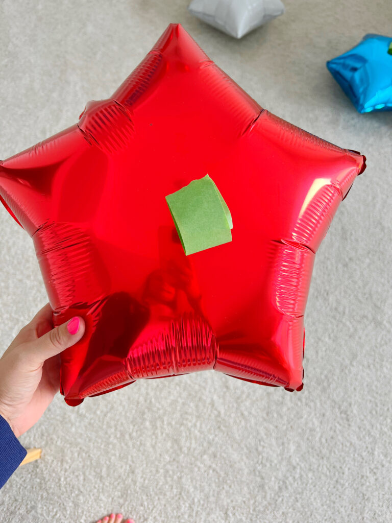 Red foil star balloon with painters tape on the back of it. 