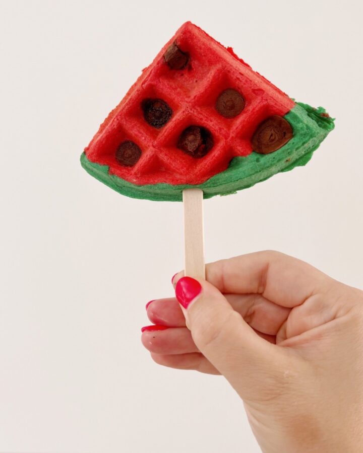 waffle on a stick made to look like a watermelon slice with chocolate chips.