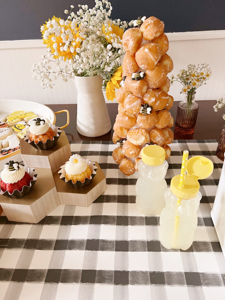 donut hole tower, flowers, lemonade in honey containers and cupcakes on table. 