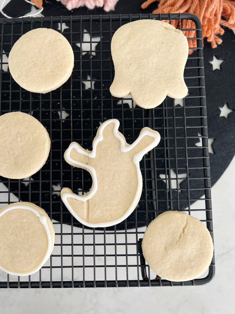 Sugar cookies being outlined with white icing. 