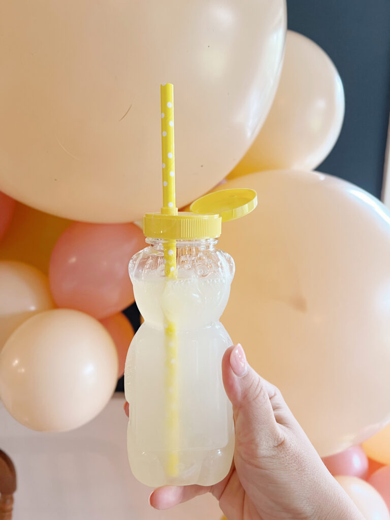 honey bear jar filled with lemonade in and with a yellow paper straw. 