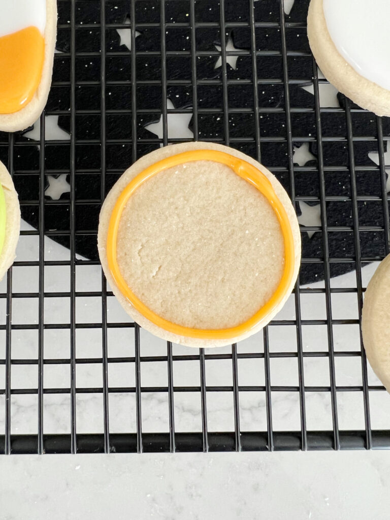 Circle shaped sugar cookie with orange icing outline. 