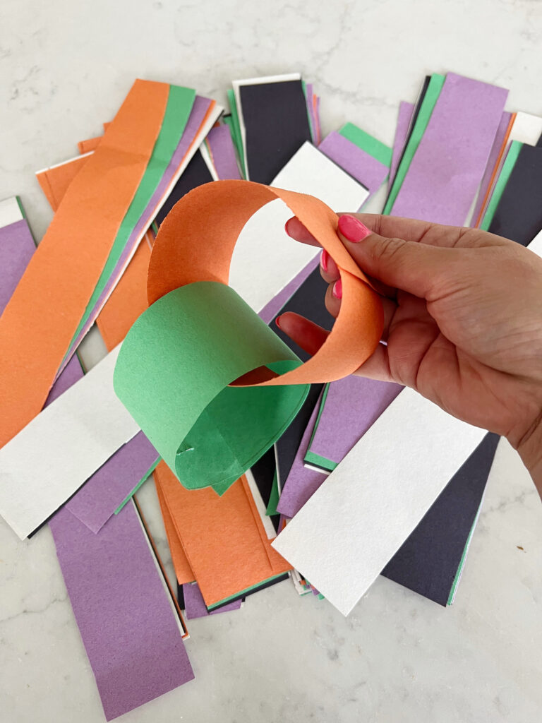 orange paper ring being stapled together to make a paper chain.