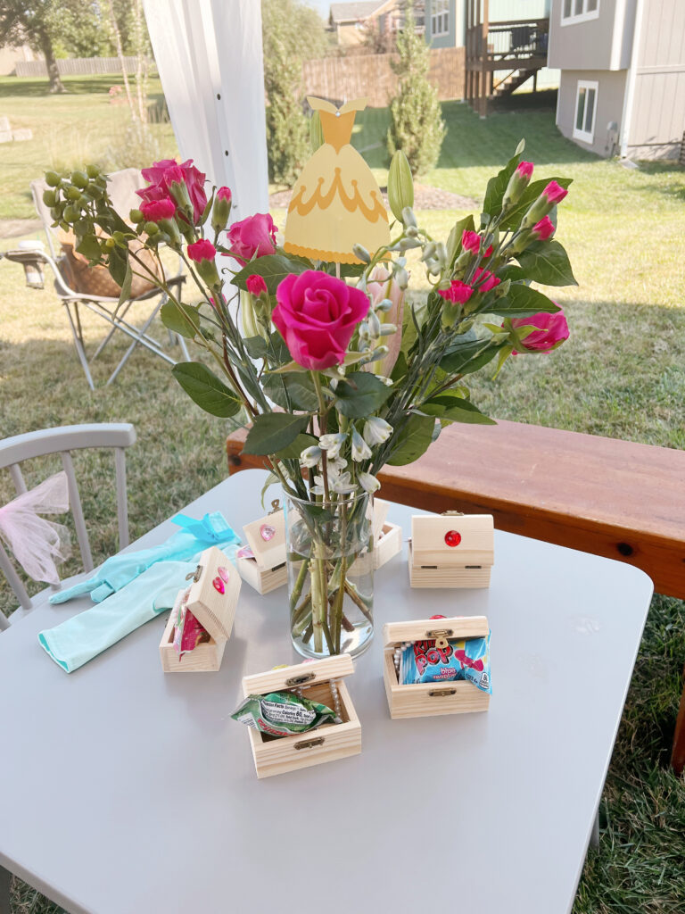 Flowers in a vase on a table with princess themed favors.