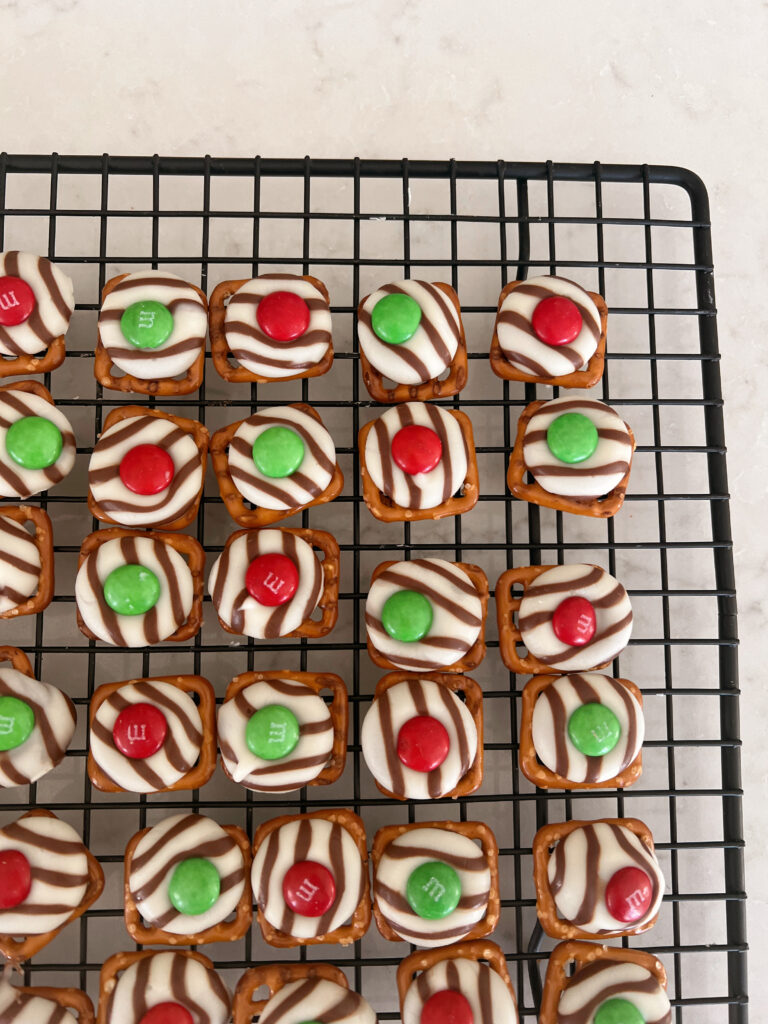 Grid pretzels with melted chocolate and m&m's on a cooling tray. 