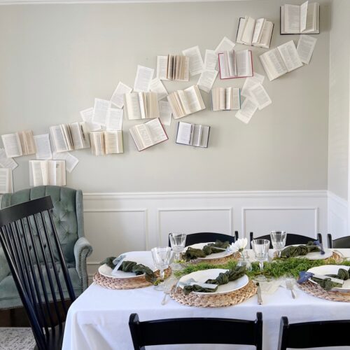 a room with open books attached to the wall and a tablescape for a baby shower.