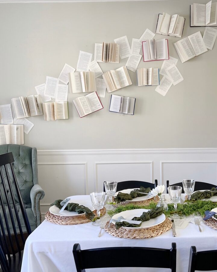 a room with open books attached to the wall and a tablescape for a baby shower.