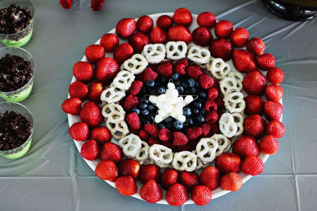 Strawberries, yogurt pretzels, raspberries, and blueberries and mini marshmallow arranged to look like a captain america shield.